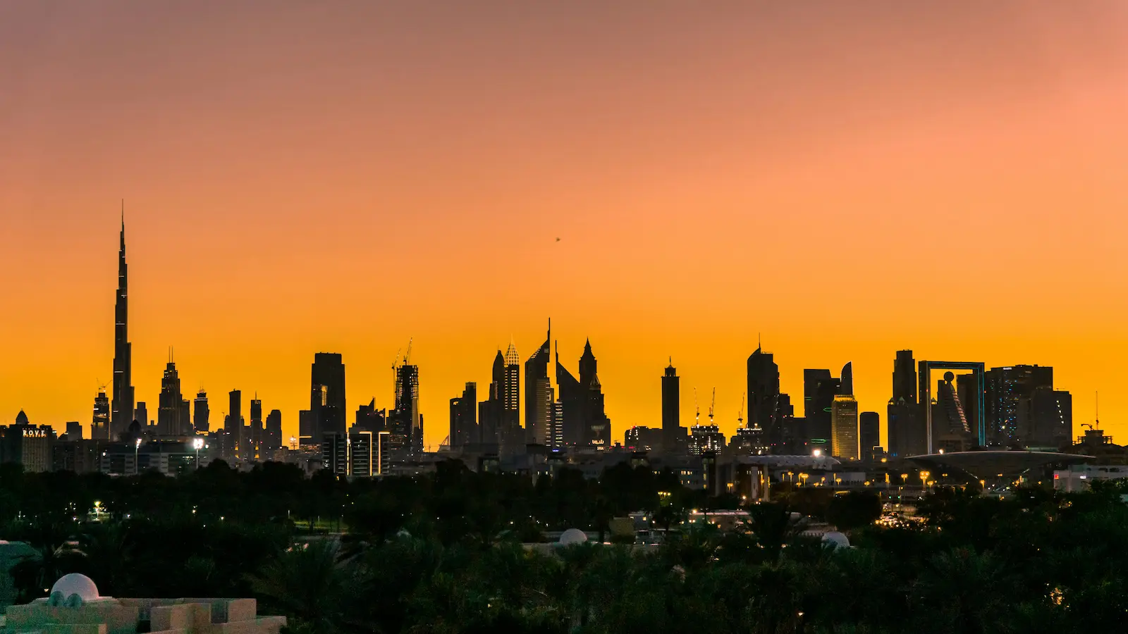 Dubai skyline silhouetted against an orange sunset sky